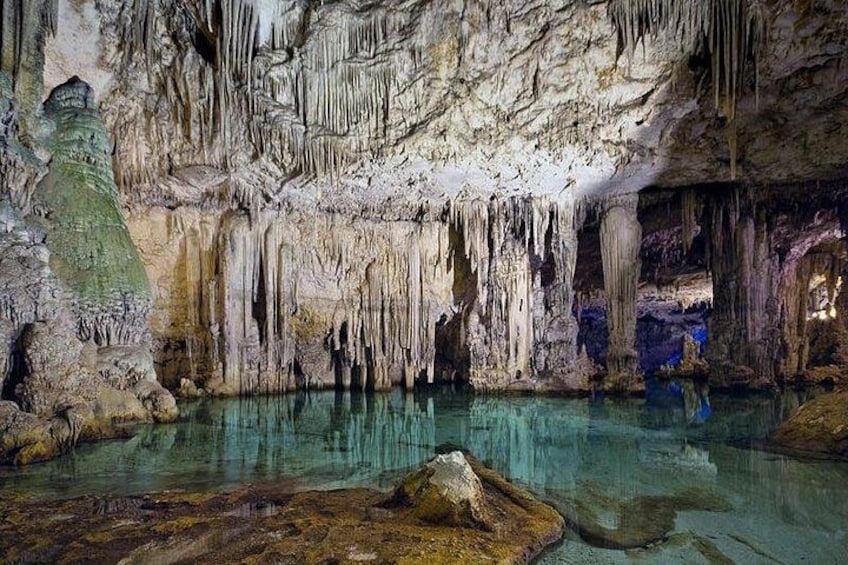 Une grotte ornée de stalactites et de stalagmites, avec de l’eau claire et des formations rocheuses. 1