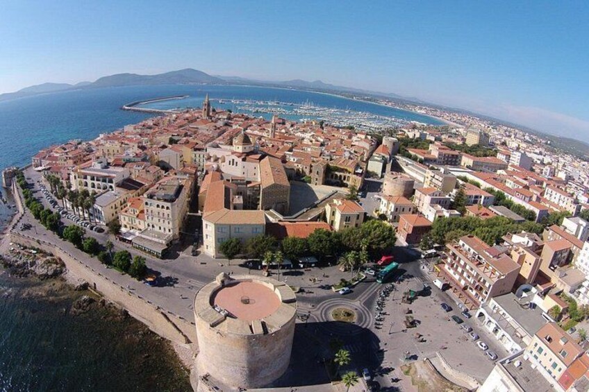 A coastal town with a prominent tower, a marina, and a mix of historic and modern buildings. 1
