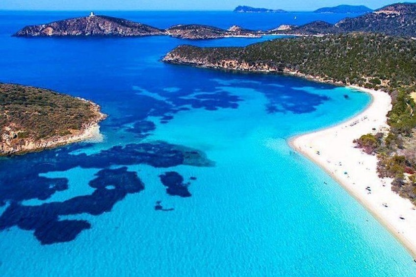 A coastal landscape with clear blue waters, a sandy beach, and rocky outcrops. 2