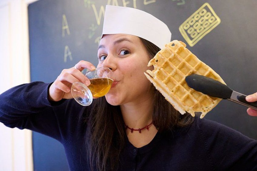 A person wearing a chef's hat, holding a waffle, and a glass of liquid. 1