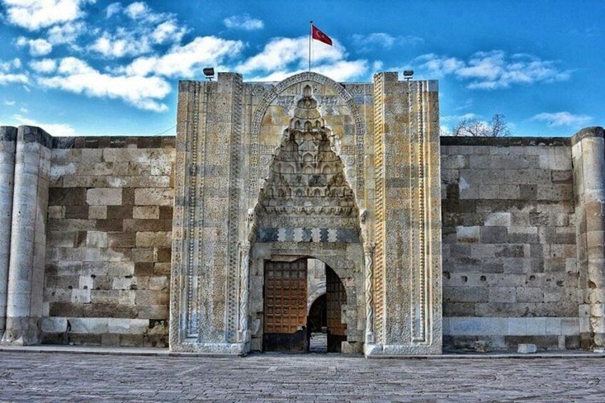 A stone archway with intricate carvings and a flag on top. 5
