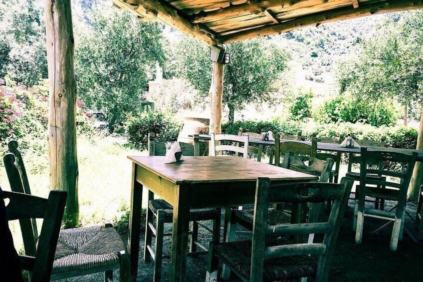 Un tavolo e sedie di legno all'aperto sotto un pergolato, con vista su un giardino e alberi. 5