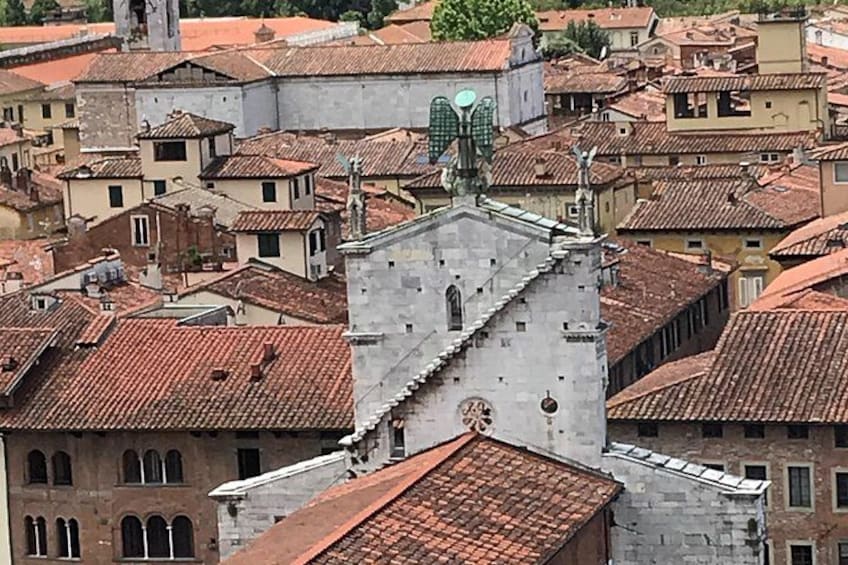 Una zona urbana densa con tejados de tejas rojas, una iglesia destacada con un campanario y una mezcla de edificios históricos y modernos. 3