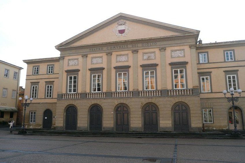 A classical building with a central entrance, arched windows, and a balcony. 2