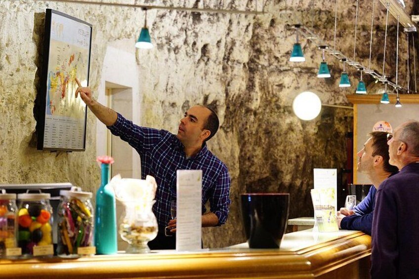 Una persona señala un menú en un restaurante rústico con un fondo de pared de piedra y luces colgantes. 3