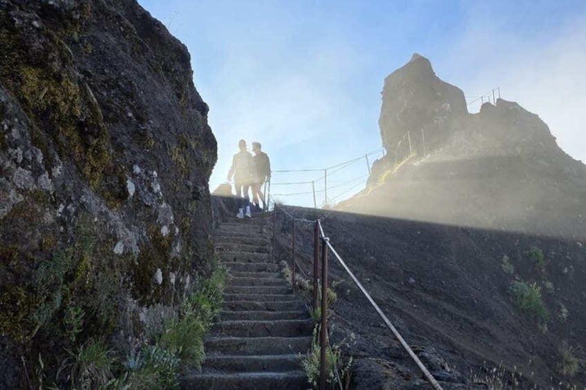 Eine Treppe führt einen felsigen Hang hinauf, zwei Personen steigen hoch. 4