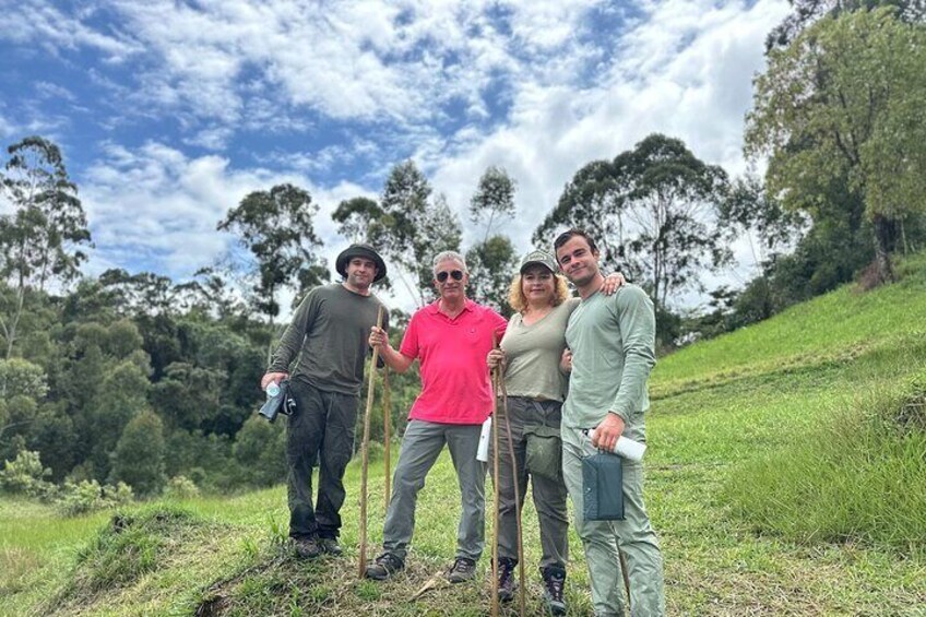 Four people standing on a grassy hill with trees in the background. 2