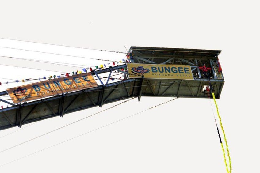 A bungee jumping platform with a banner reading 'BUNGEE Pokhara Nepal' and a yellow safety rope. 3