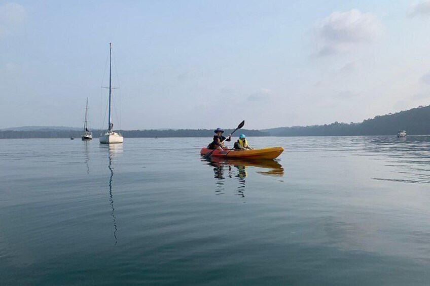A calm lake with a kayak and sailboats. 3