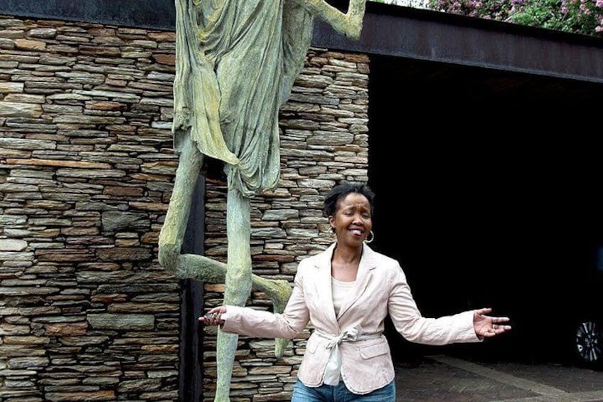 A person standing in front of a stone wall with a large sculpture. 5