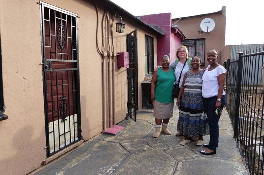 A group of people standing in front of a building with a gated entrance and satellite dish. 2