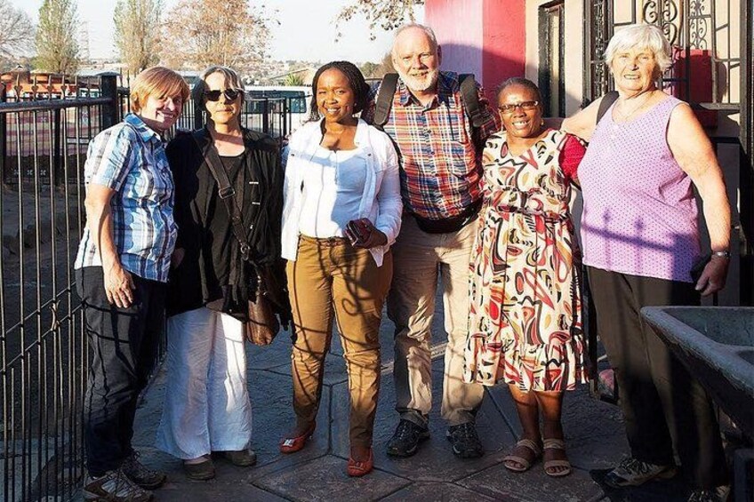 A group of people standing on a paved area with a metal fence in the background. 3