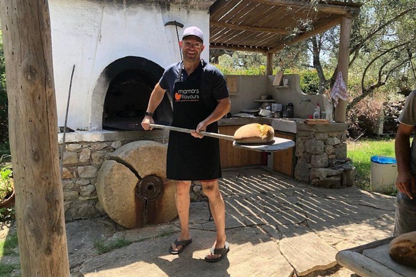 A person holding a pizza peel in front of a wood-fired oven. 3