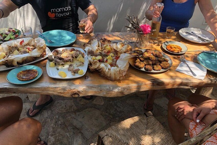 A wooden table with various dishes of food, a pitcher, and a glass of drink. 4