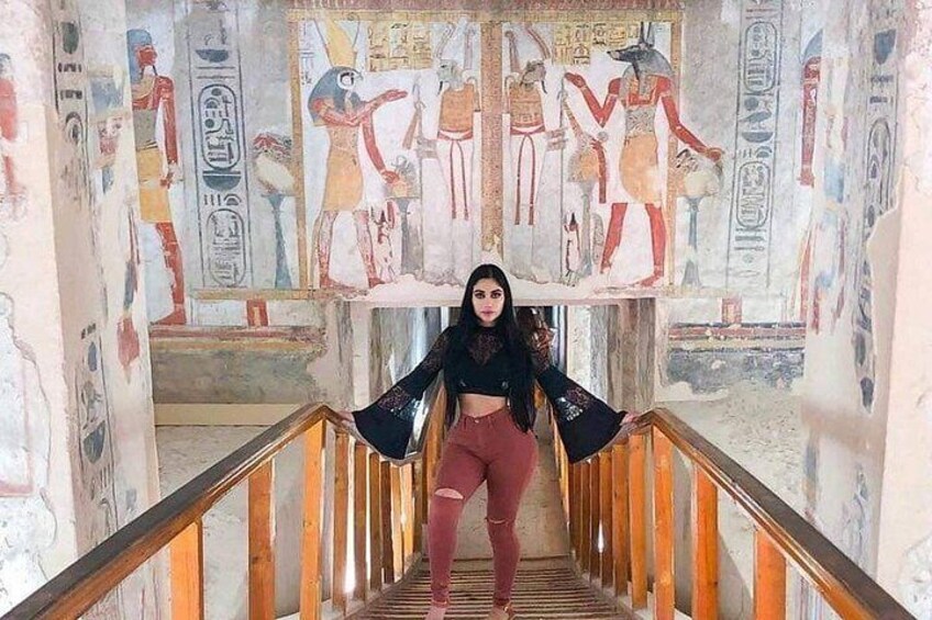 A person standing on a staircase with ancient Egyptian wall paintings. 4