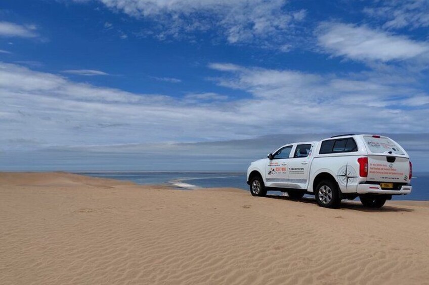 Un véhicule blanc est garé sur une plage de sable, sous un ciel dégagé. 4