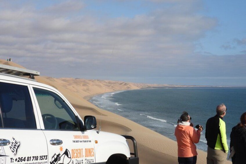 Un paysage désertique avec un véhicule blanc garé sur la plage, un ciel dégagé et une mer calme. 3