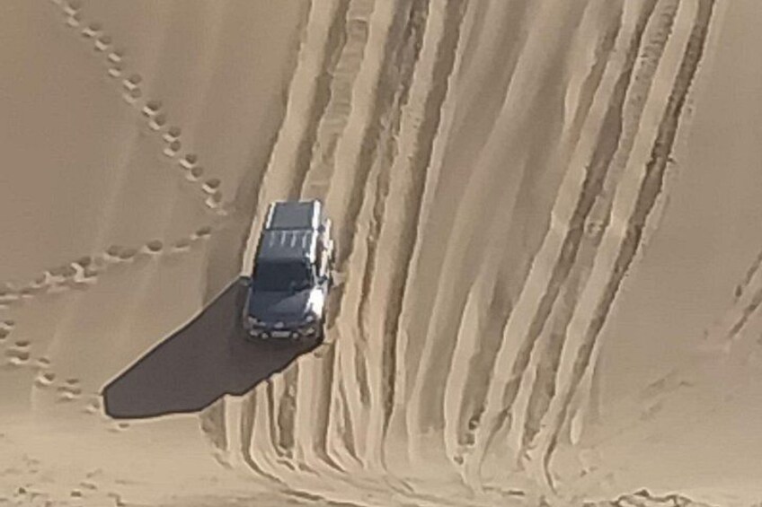 A vehicle driving on a sandy road with tire tracks. 2