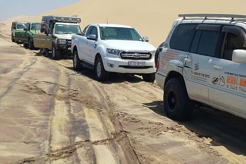 Un convoi de véhicules sur une route de sable, dans un désert. 2