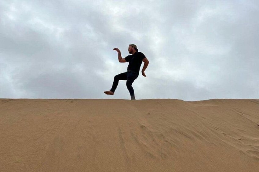 A person jumping on a sand dune. 3