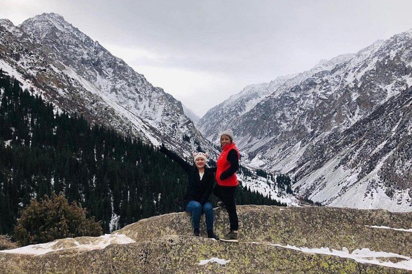 Två personer står på en klippavsats med snötäckta berg i bakgrunden. 5