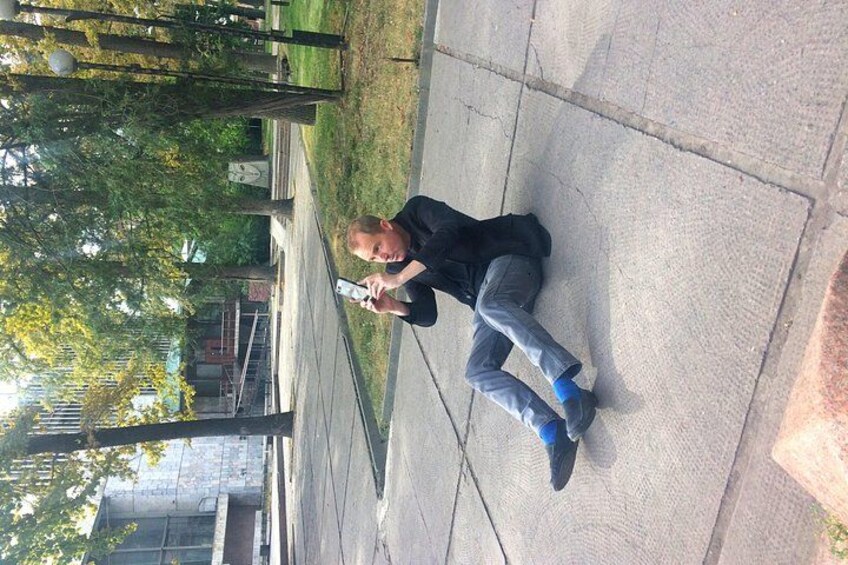 En person sitter på en trottoar i en park och håller i en smartphone. 3