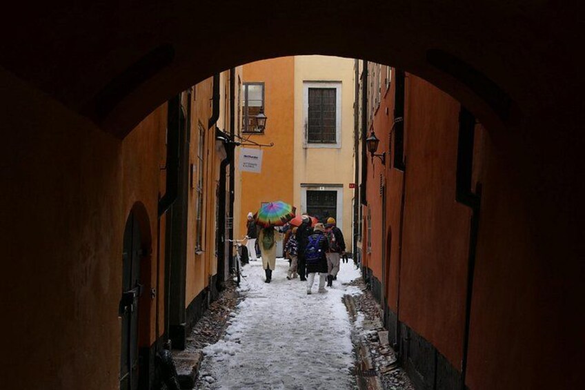 Ein schmaler Gang mit Schnee auf dem Boden, Passanten und Häuser mit Rundbogenportalen. 2