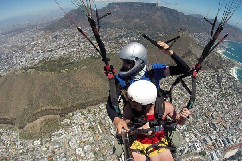 To personer paraglider med en by og bjerge i baggrunden. 5