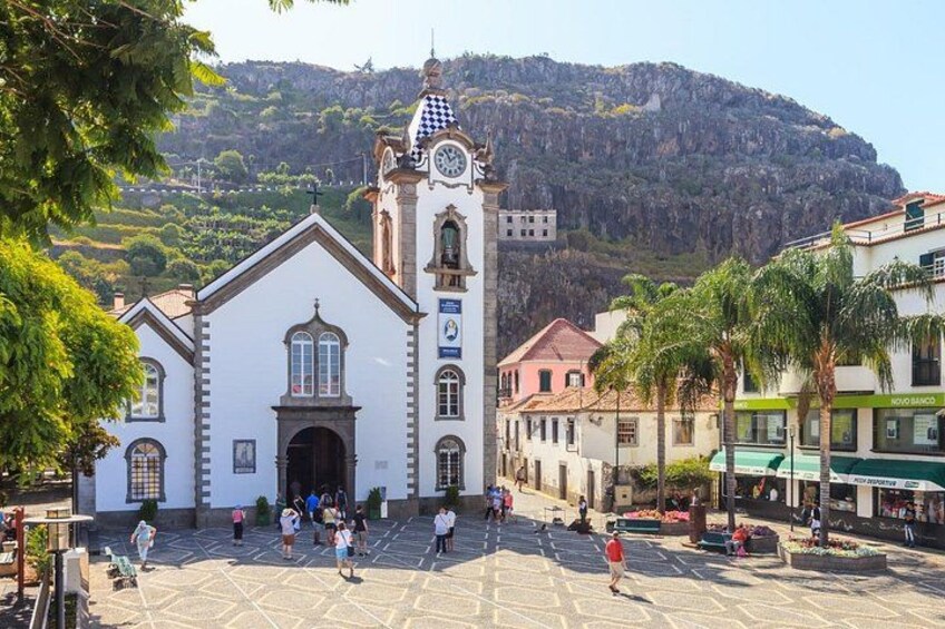 Una piazza cittadina con una chiesa, un campanile e edifici con negozi. 3