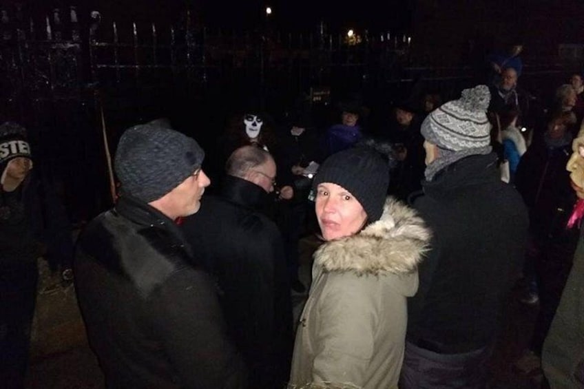 Un grupo de personas al aire libre de noche, algunas vestidas con ropa de invierno. 1