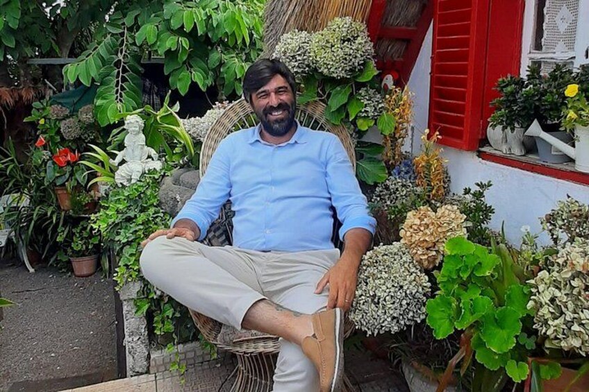 A man sitting on a chair surrounded by various potted plants and flowers. 3