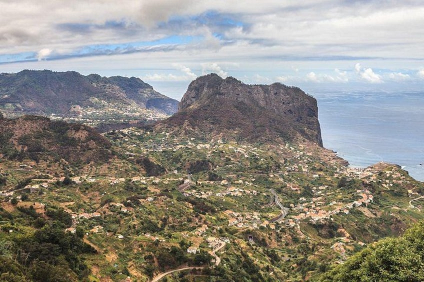 A mountainous landscape with a coastal view, featuring a prominent cliff and scattered settlements. 2