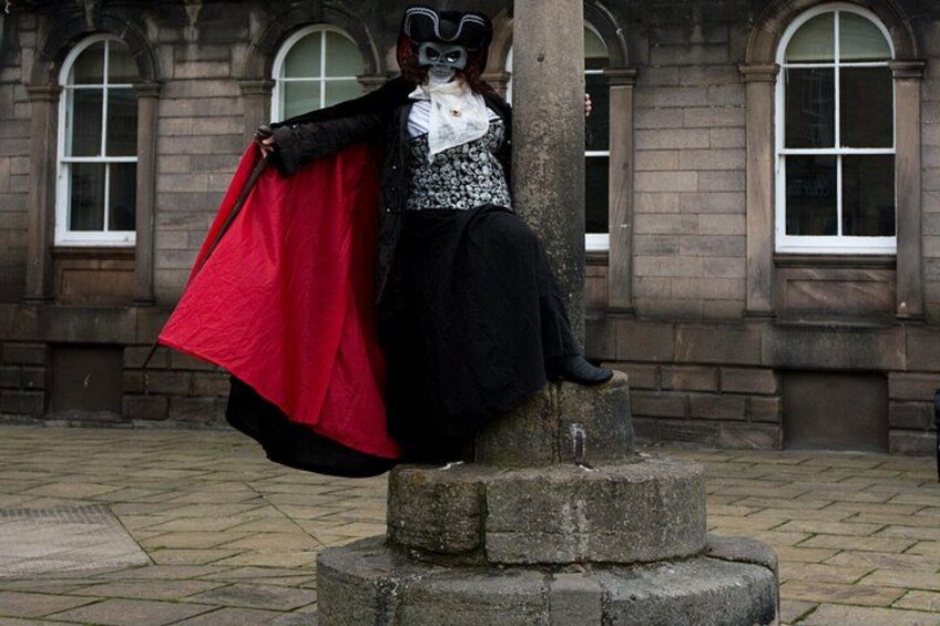 Una estatua de una persona vestida de negro y rojo sentada sobre un pedestal de piedra. 4