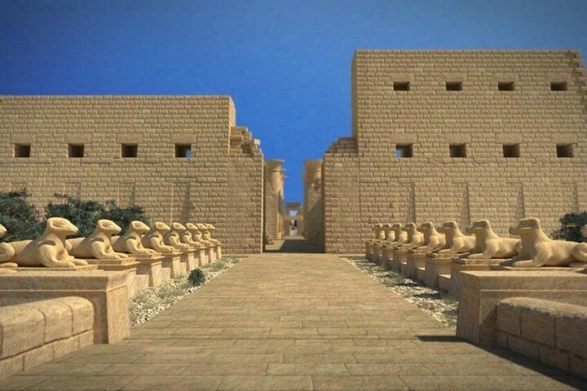 Un vialetto costeggiato da file di statue di sfingi conduce a un grande edificio con un ingresso a gradoni. 2