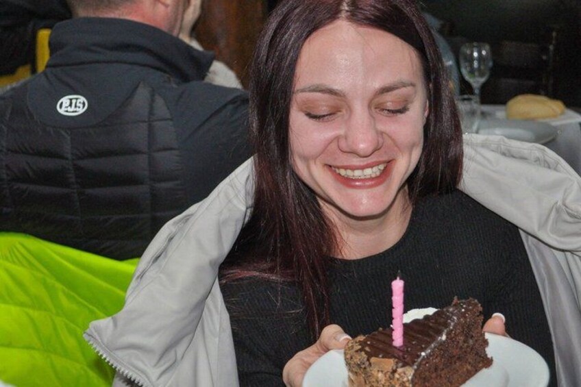 Una persona sosteniendo una porción de pastel con una vela encendida. 3