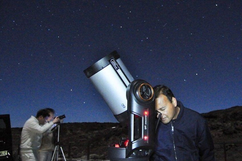 A person using a telescope under a starry night sky. 2