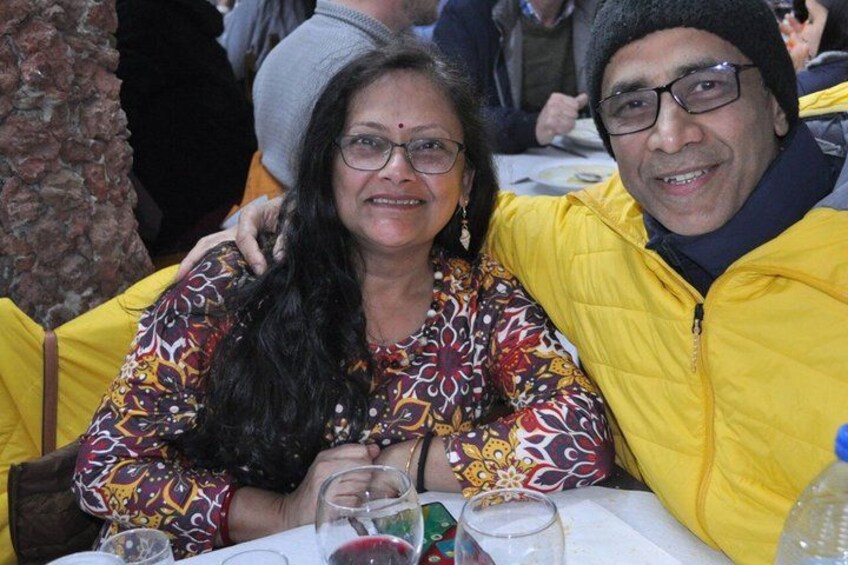 Dos personas sentadas a una mesa con una botella de agua y una copa de vino tinto. 5