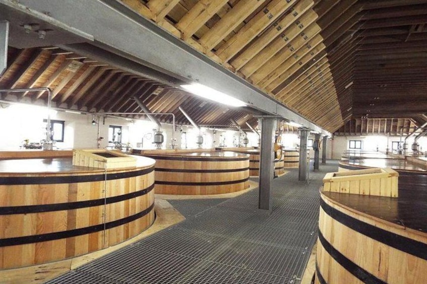 A large wooden barrel facility with multiple barrels arranged in rows. 3