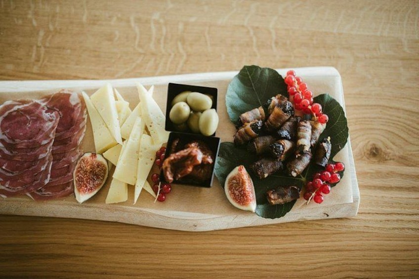 A wooden board with various food items including cheese, figs, and cured meats. 3