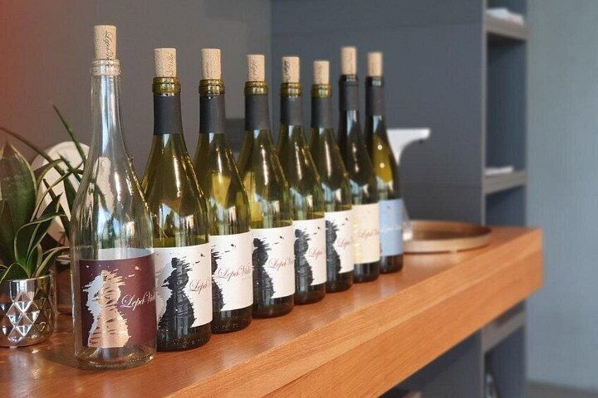 Varias botellas de vino en un estante de madera con etiquetas. 4
