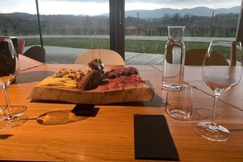 A wooden table with a plate of food, wine glasses, and a smartphone. 2