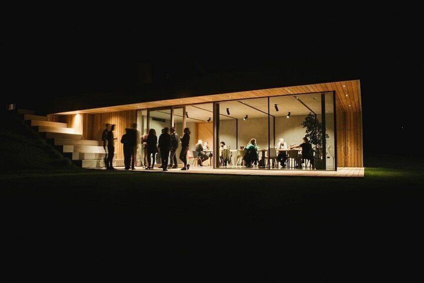 Un edificio moderno con paredes de vidrio, escalones de madera y gente en su interior. 3