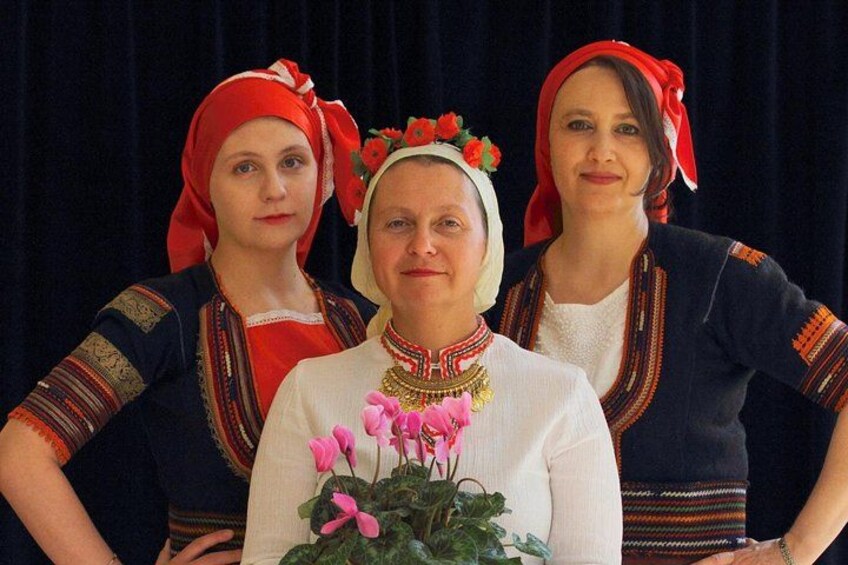 Drie personen in traditionele kleding met bloemen in het haar en sieraden. 5