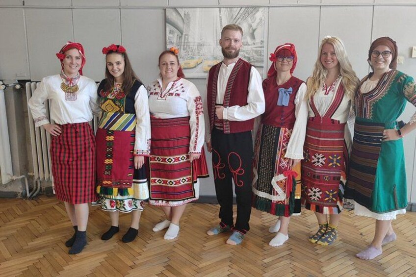Een groep mensen in traditionele kledij staat binnen. 4