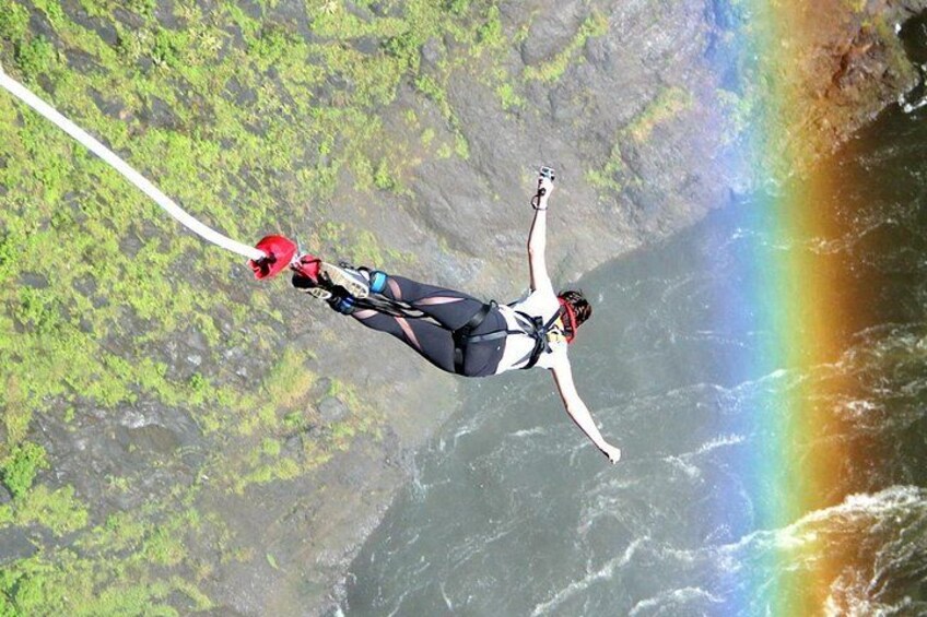 A person bungee jumping with a rainbow in the background. 1