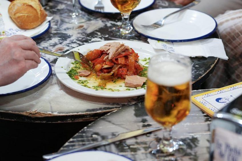 A dining table with plates of food, a glass of beer, and a person eating. 4