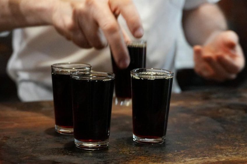 Three glasses of a dark liquid on a wooden surface. 3