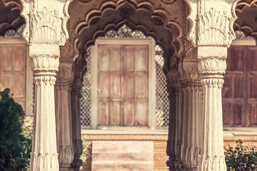 An ornate architectural structure with carved columns and a wooden door. 4