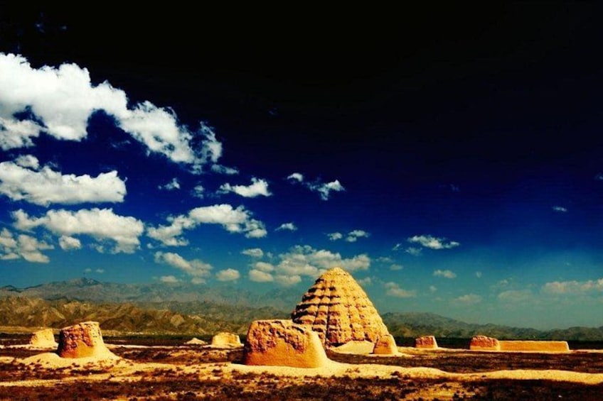 A desert landscape with large rock formations under a blue sky with clouds. 1