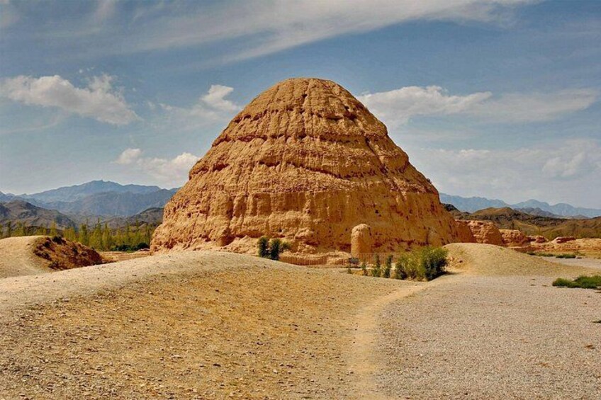 A large rock formation in a desert landscape with mountains in the background. 2